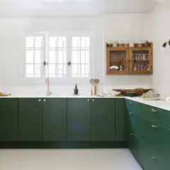 Cuisine moderne avec des armoires vert forêt profond. La couleur mur cuisine est blanc cassé, contrastant avec les meubles sombres.