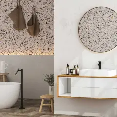 Élégante salle de bain terrazzo avec baignoire, lavabo moderne et miroir rond.