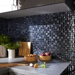 Crédence noire brillante, idéale pour une cuisine moderne. Des herbes fraîches, des oignons et des noix sur le plan de travail. Quelle crédence choisir pour un style audacieux ?