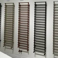 Cinq sèche-serviettes de différentes couleurs (noir, bronze, marron, noir, gris) sont alignés. La hauteur de ces sèche-serviettes est impressionnante.