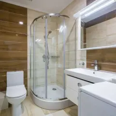 Salle de bain moderne avec douche à l'italienne, lavabo, WC et un banc intégré dans la douche pour plus de confort.