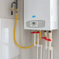 Installation d'un nouveau ballon d'eau chaude Baxi. Tuyaux de gaz et d'eau avec robinets rouges.