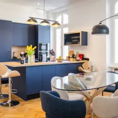 Une belle idée cuisine ouverte sur salon avec des meubles bleus profonds, un îlot central et une table en verre.