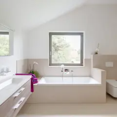 Salle de bain moderne avec baignoire, lavabo et WC suspendu. La séparation salle de bain avec wc est subtile, créant un espace fluide et lumineux.