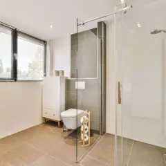Salle de bain moderne avec douche italienne surélevée avec marche, toilettes suspendues et meuble vasque.