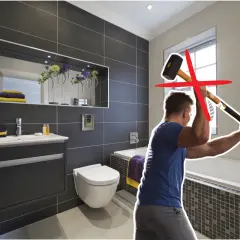Un homme s'apprête à démolir une salle de bain moderne avec une masse. Une croix rouge indique que cette méthode n'est pas recommandée pour la renovation carrelage.