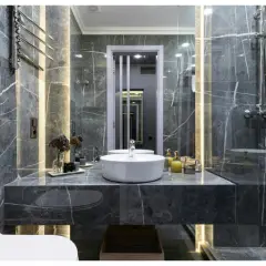 Une **salle de bain de rêve** aux murs de marbre gris, avec vasque ronde, douche moderne et éclairage d'ambiance.