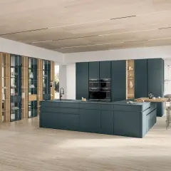 Un sol de cuisine tendance en travertin clair, réchauffant cet espace moderne aux meubles bleu pétrole.