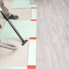 Préparation du sol avant la pose du parquet : nettoyage avec aspirateur. Le temps de séchage du ragréage est crucial.