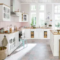 Une cuisine campagne chic lumineuse avec des meubles blancs, un plan de travail en bois, un carrelage coloré et de grandes fenêtres donnant sur le jardin.