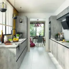 Cuisine moderne avec des meubles gris béton, une cuisine en parallèle fonctionnelle et un espace repas lumineux visible à travers une arche.