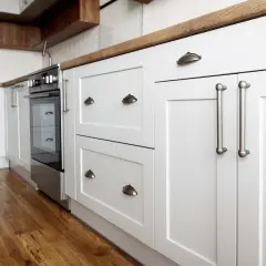 Cuisine moderne avec meubles blancs et poignées argentées. Un projet de rénovation de meuble cuisine réussi, alliant style et fonctionnalité.