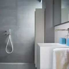 Salle de bain moderne avec douche sans carrelage, lavabo blanc et accessoires bleus.