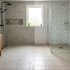 Salle de bain moderne avec béton ciré sur un mur, montrant un inconvénient potentiel : la saleté visible. Douche carrelée à côté.