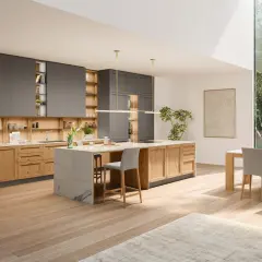 Cuisine moderne avec îlot central en marbre, meubles en bois et gris, et grande fenêtre donnant sur la verdure. Parfaites idées cuisine pour un espace lumineux.