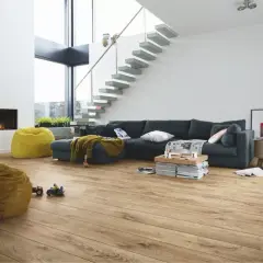 Salon moderne avec canapé, cheminée, poufs et escalier flottant. Le parquet flottant, d'une épaisseur idéale, réchauffe l'espace.
