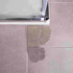 Une fuite sous le bac à douche, une situation qui peut nécessiter une intervention d'assurance. L'eau s'est répandue sur le carrelage.