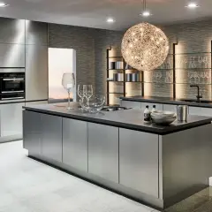Une cuisine chic et moderne aux finitions métalliques, avec un îlot central, des fours intégrés et des étagères lumineuses.