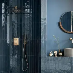 Élégante salle de bain bleu nuit avec douche à l'italienne carrelée, miroir rond en bois et vasque en béton.