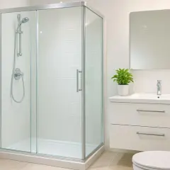 Salle de bain moderne avec douche vitrée, lavabo, miroir et WC. Idéal pour un nettoyage facile et une ambiance zen.