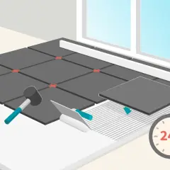 Pose de carrelage au ciment : une nouvelle dalle est posée sur la colle fraîche. Un marteau et une spatule sont prêts. Le séchage prend 24h.