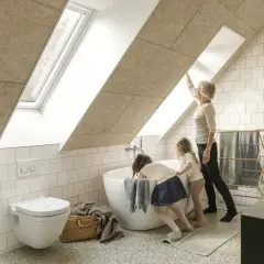 Salle de bain sous pente avec wc suspendu. Une femme et deux enfants admirent la lumière entrant par la fenêtre de toit.