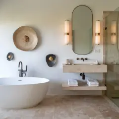 Salle de bain moderne avec baignoire îlot, lavabo en pierre et douche à l'italienne. Le sol et les murs de la douche sont en travertin 1er ou 2ème choix, apportant une touche naturelle et élégante.