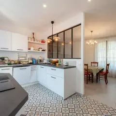 Carrelage décoratif au sol pour la délimitation carrelage cuisine salon. Une cuisine moderne blanche ouverte sur une salle à manger avec lustre.