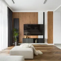 Un salon moderne avec un sol en parquet en chevrons, un mur texturé en bois et un meuble TV suspendu. Un mélange de carrelage et de parquet crée une transition élégante.