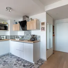 Cuisine 10m2 fermée, moderne et fonctionnelle avec placards blancs, carrelage géométrique et plan de travail en bois.