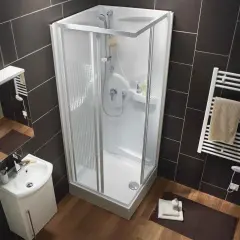 Salle de bain moderne avec une cabine de douche aux dimensions compactes, un lavabo suspendu et un sèche-serviettes.