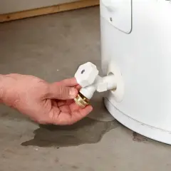 Main tenant connectant un tuyau à la vanne pour comment vider un ballon d'eau chaude.