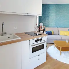Plan d'une petite cuisine en U moderne avec évier, plaque de cuisson, four et un salon cosy avec canapé bleu et jaune.