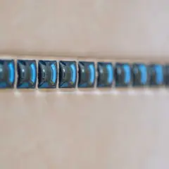 Ligne de petites mosaïques bleues, comme une frise, à une certaine hauteur sur un mur de salle de bain.