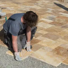 Un ouvrier pose des dalles de travertin pour créer une terrasse.