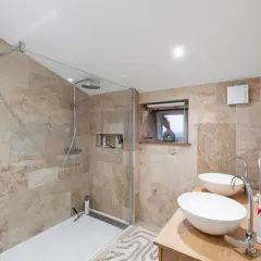 Salle de bain moderne avec douche à l'italienne et double vasque, une belle rénovation faience salle de bain en pierre naturelle.