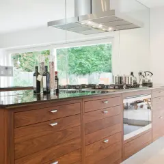 Cuisine moderne avec îlot central en bois, hotte en inox et vue sur jardin. Une belle rénovation pour une vieille cuisine.