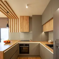 Cuisine moderne avec home staging réussi, mêlant bois chaleureux et finitions grises élégantes. L'îlot central en bois et les suspensions créent une ambiance accueillante.