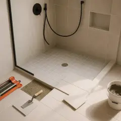 Pose de carreaux pour le revêtement sol douche italienne. Outils de pose à portée de main.