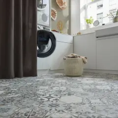 Buanderie moderne avec un sol en carrelage hexagonal aux motifs vintage. Une machine à laver et un panier à linge sont visibles.
