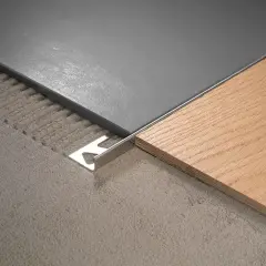Le sol présente 2 carrelages différents : un gris moderne et un imitation bois chaleureux, séparés par une plinthe métallique.