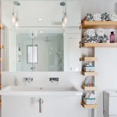 Étagères flottantes en bois pour une astuce rangement petite salle de bain. Serviettes roulées, produits de toilette et décorations y trouvent leur place.