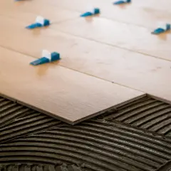 Pose d'un carrelage 60x120 pose décalée, avec des croisillons bleus et blancs assurant un espacement parfait pour un rendu impeccable.