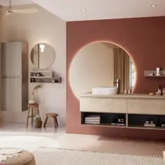 Salle de bain moderne avec murs rose terre et beige, meuble vasque en bois clair, miroir rond lumineux. La couleur salle de bain est chaleureuse et apaisante.