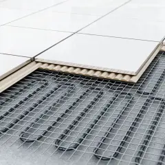 Vue en coupe d'un carrelage posé sur un système de chauffage au sol, montrant les câbles chauffants sous la dalle.
