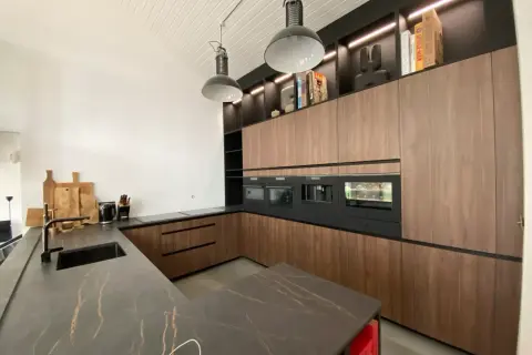 Cuisine salle à manger et salon dans la même pièce. Design moderne avec îlot central, meubles en bois, et électroménagers intégrés.