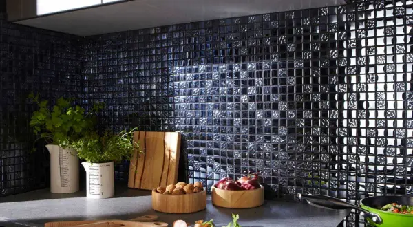 Crédence noire brillante, idéale pour une cuisine moderne. Des herbes fraîches, des oignons et des noix sur le plan de travail. Quelle crédence choisir pour un style audacieux ?