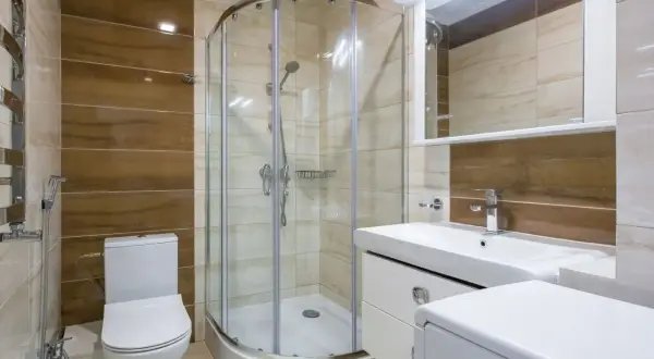 Salle de bain moderne avec douche à l'italienne, lavabo, WC et un banc intégré dans la douche pour plus de confort.