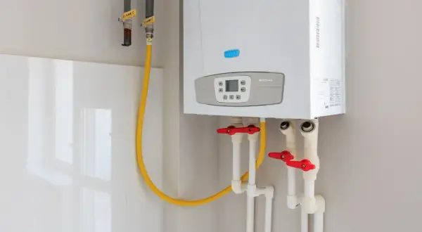 Installation d'un nouveau ballon d'eau chaude Baxi. Tuyaux de gaz et d'eau avec robinets rouges.
