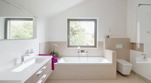 Salle de bain moderne avec baignoire, lavabo et WC suspendu. La séparation salle de bain avec wc est subtile, créant un espace fluide et lumineux.
